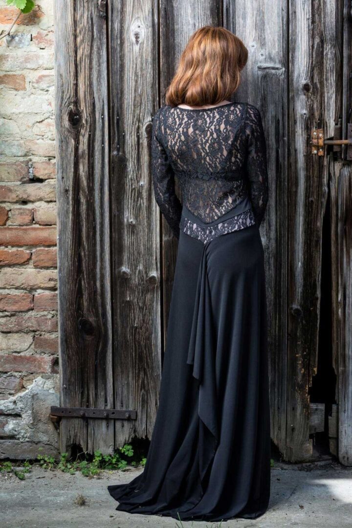A woman in a V Argentine Tango Dress standing next to a wooden door.