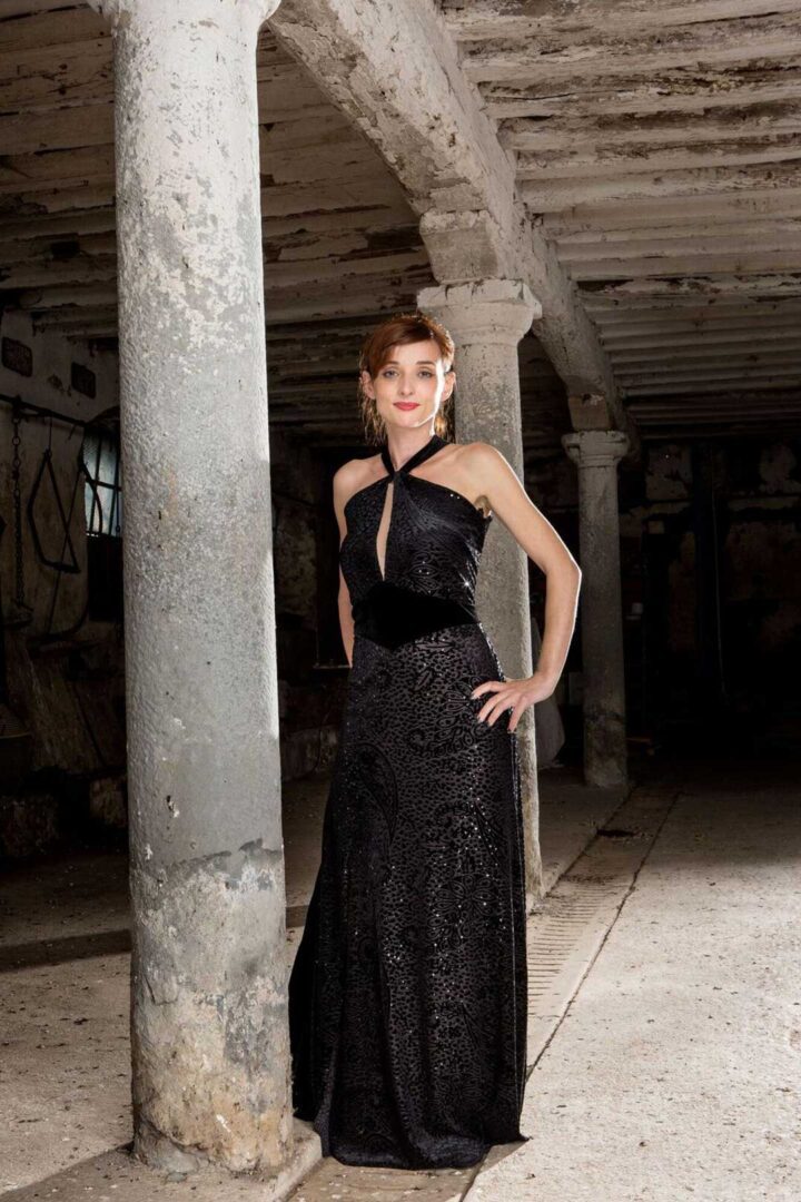A woman in a Juana evening gown posing in an old building.