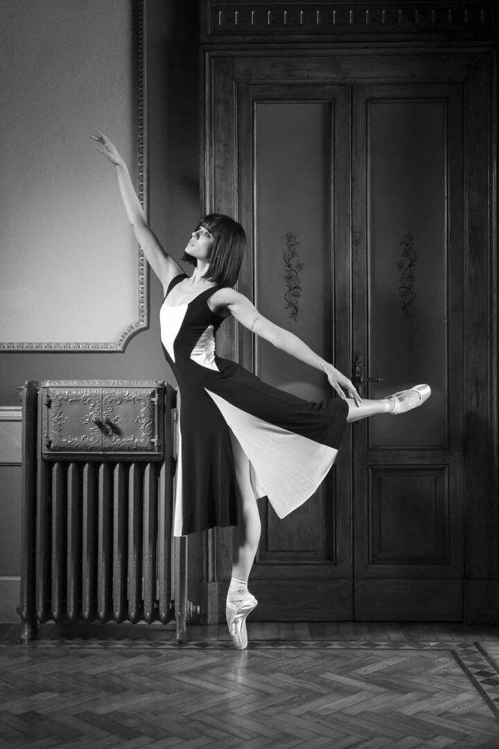A woman in a black and white dress is posing in front of a radiator.
