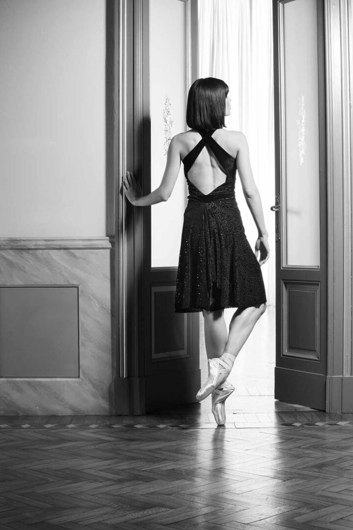 A black and white photo woman standing in an open door.