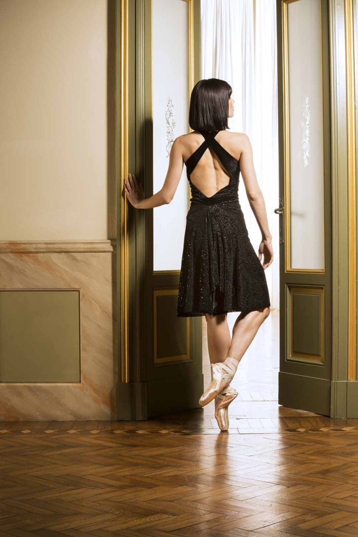 A woman in a black dress standing in an open door.