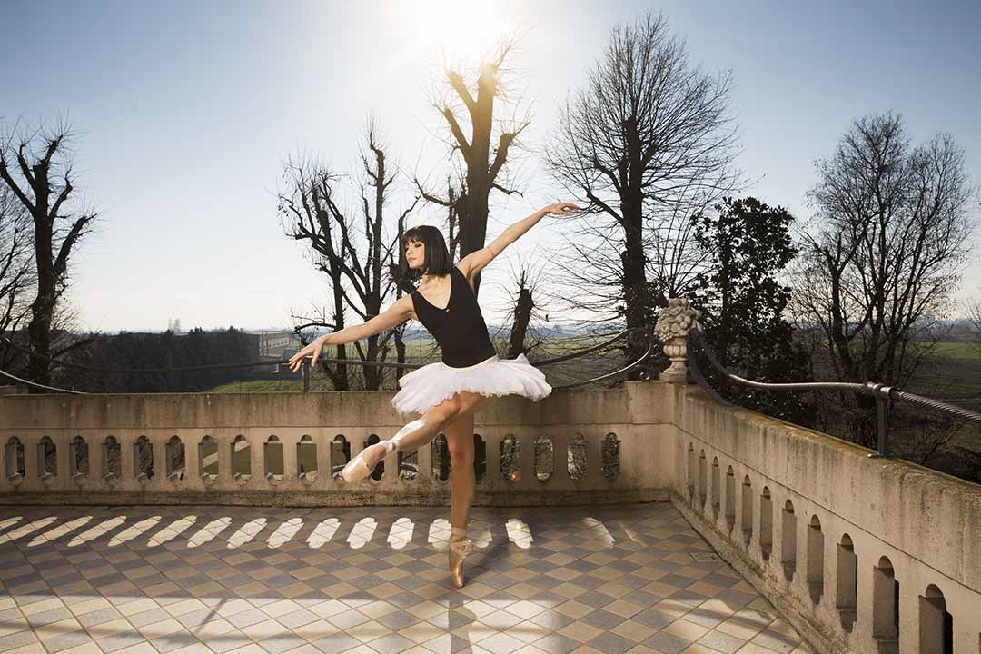 A ballerina is dancing on a balcony.