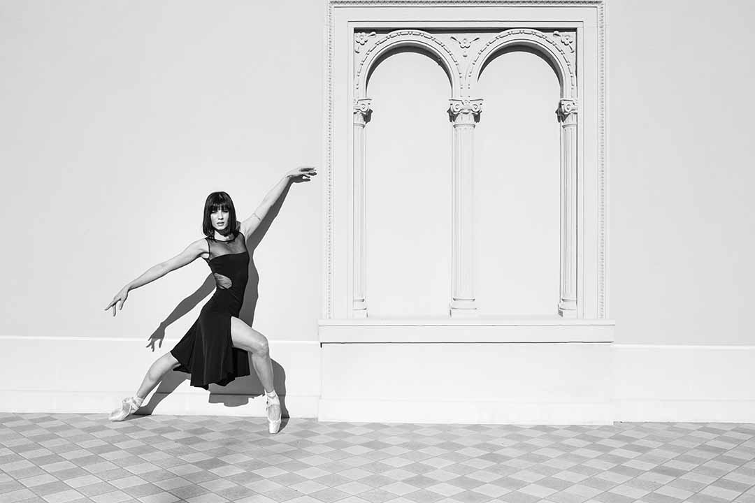 A black and white photo of a dancer leaning against a wall.