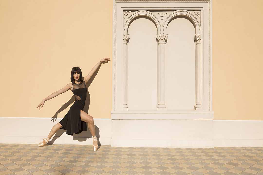 A photo of a dancer leaning against a wall.
