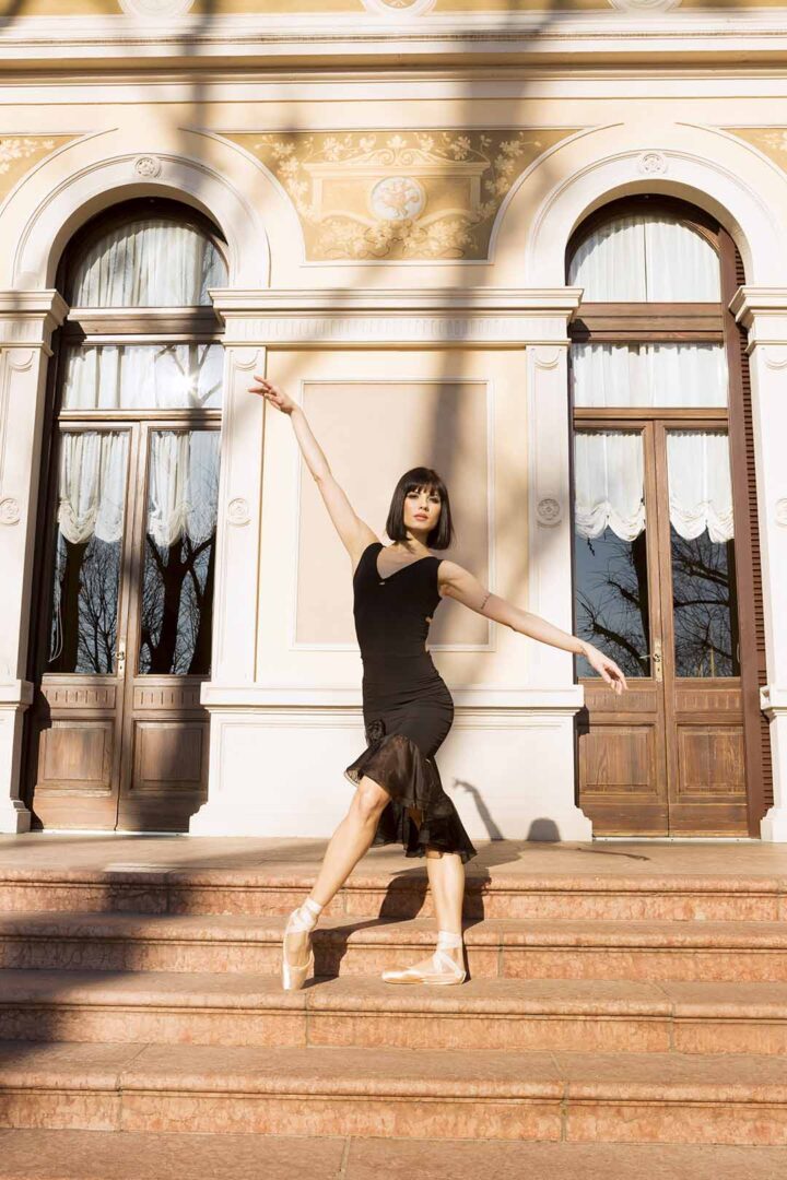 A photo of a ballerina posing in front of an old building.