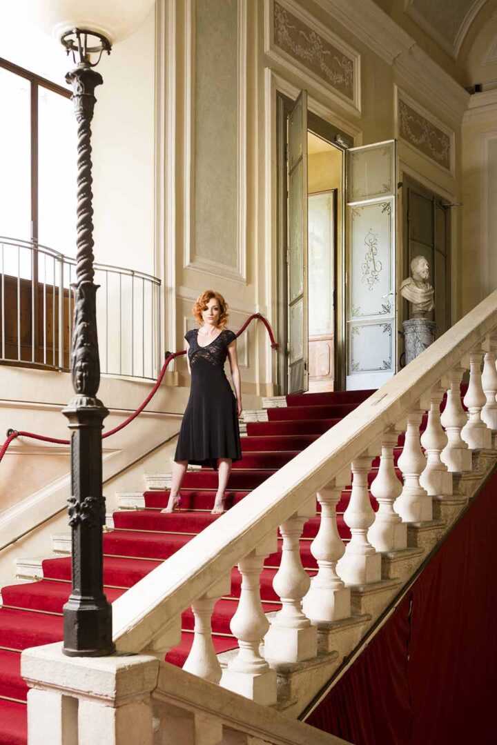 A woman in a black dress standing on a staircase.