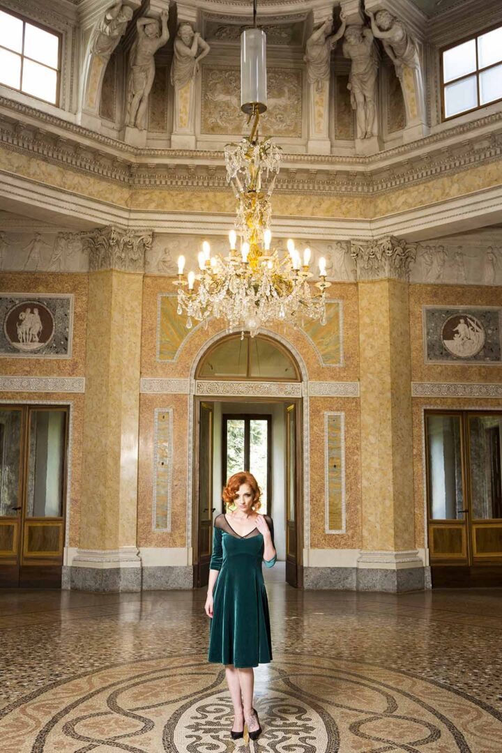 A woman in a green dress standing in an ornate room.