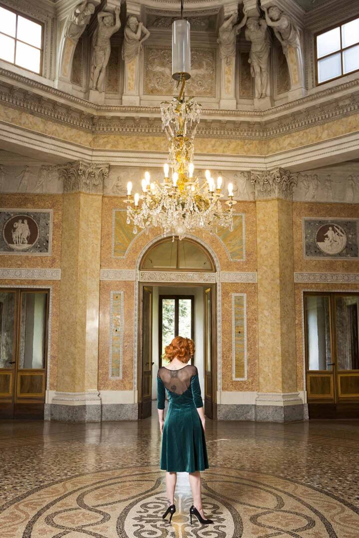 A woman standing in a room with a chandelier.