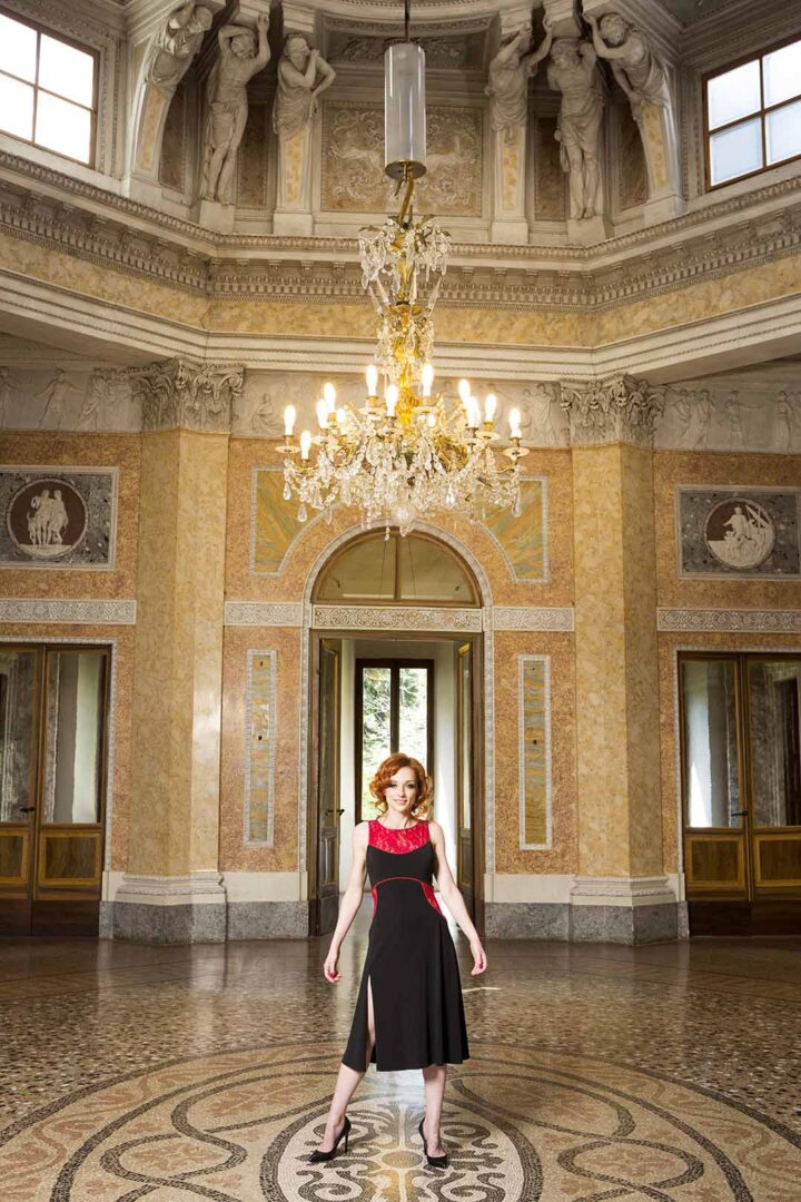 A woman in a red dress standing in an ornate room.
