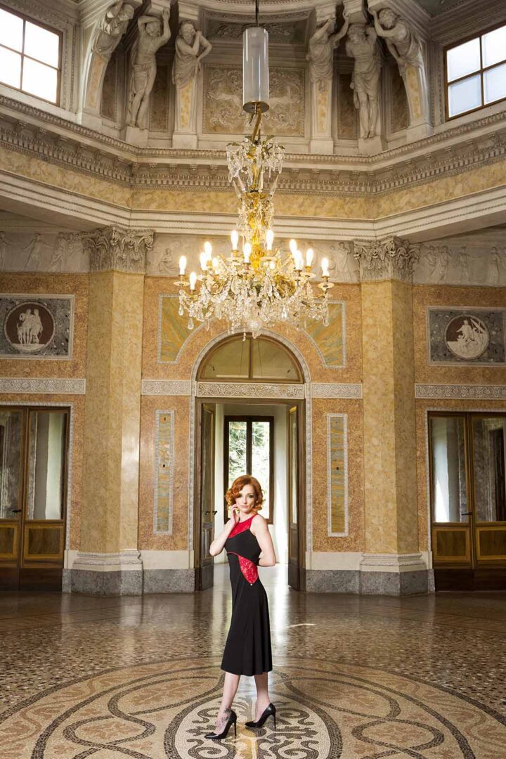 A woman in a red dress standing in an ornate room.