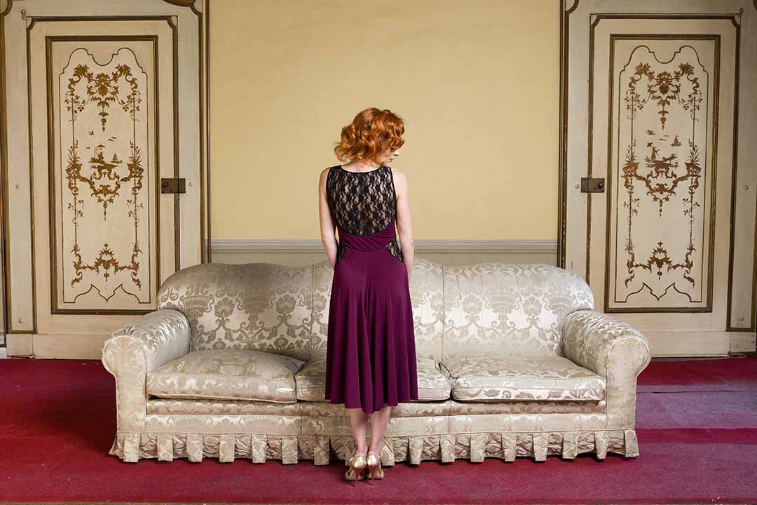 A woman is standing on a couch in a room.