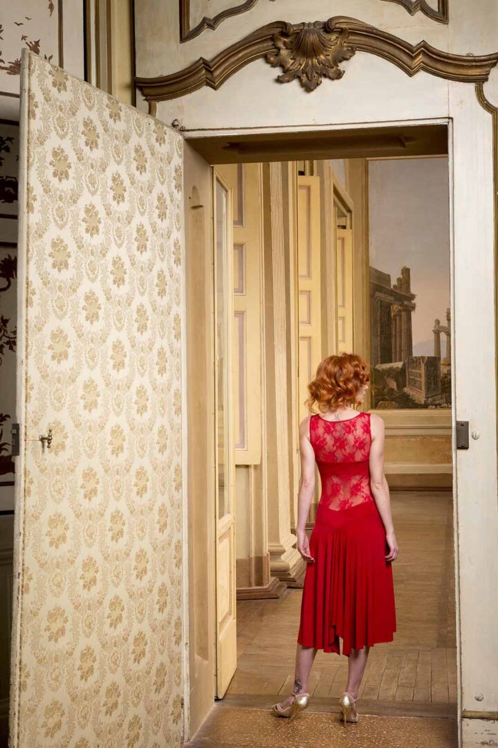A woman in a red dress standing in a doorway.