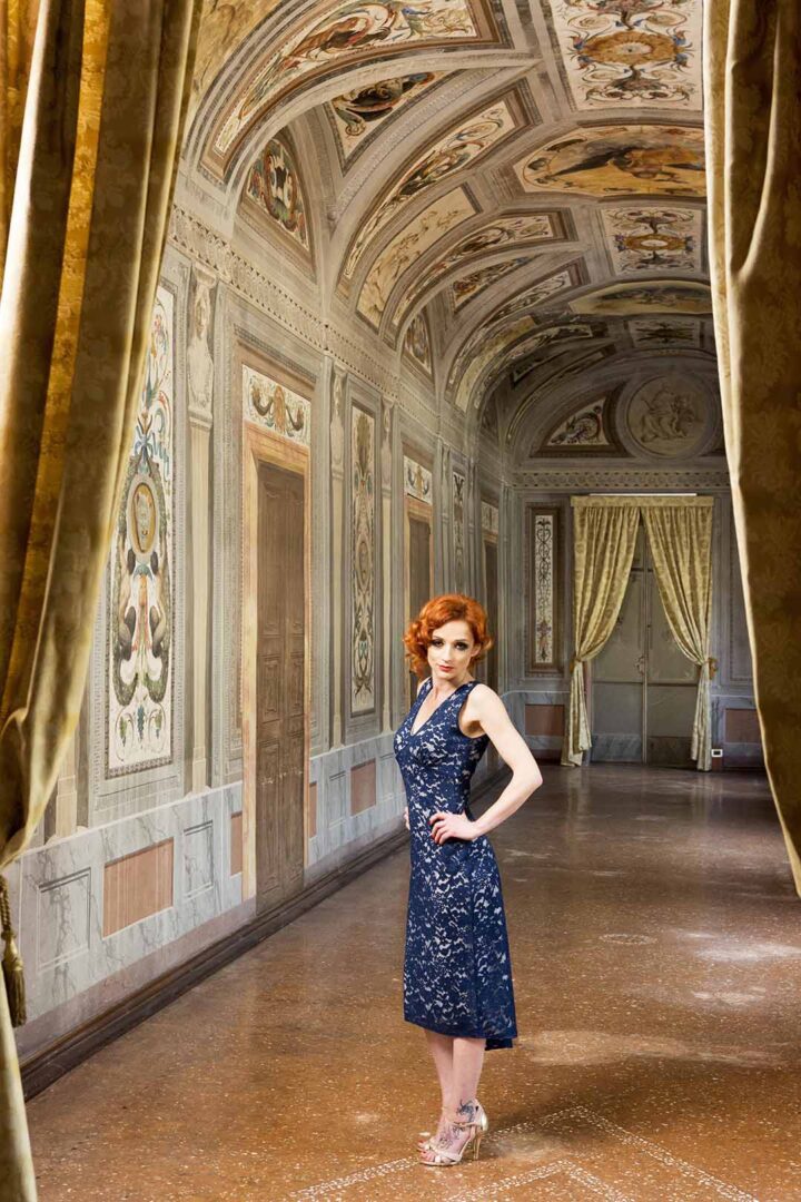 A woman in a dress standing in an ornate room.
