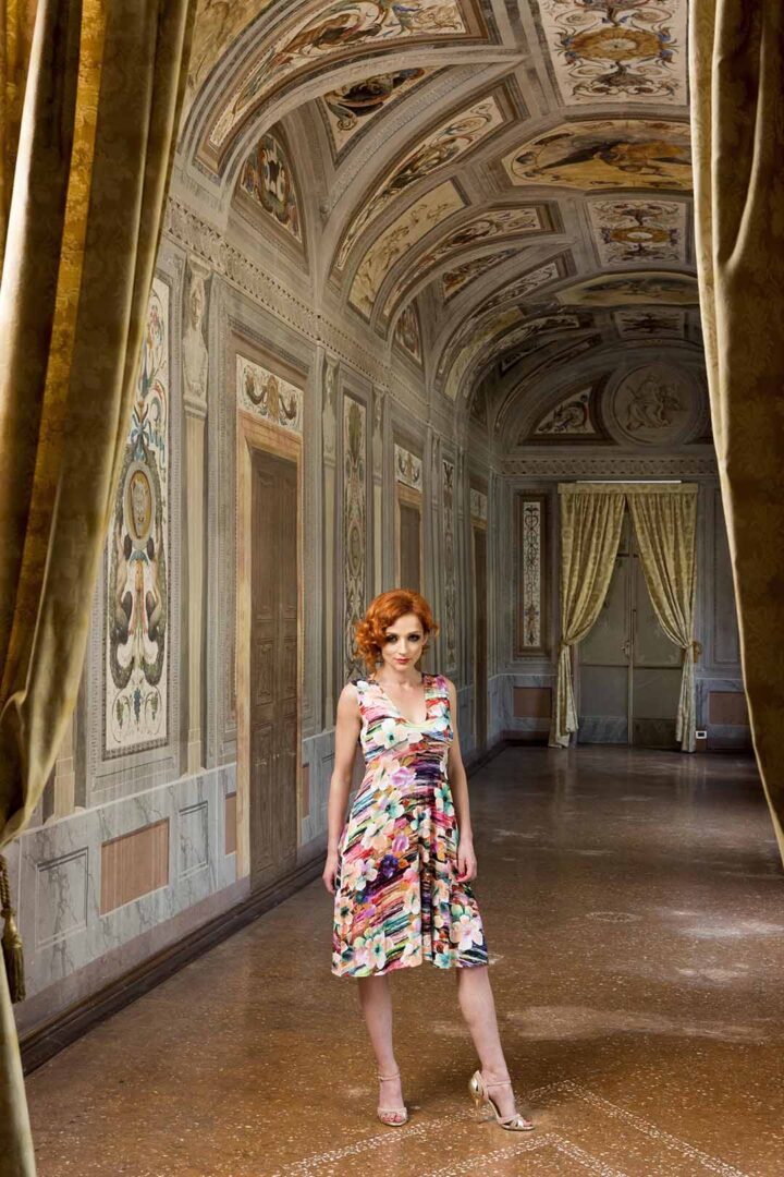 A woman in a floral dress standing in an ornate room.
