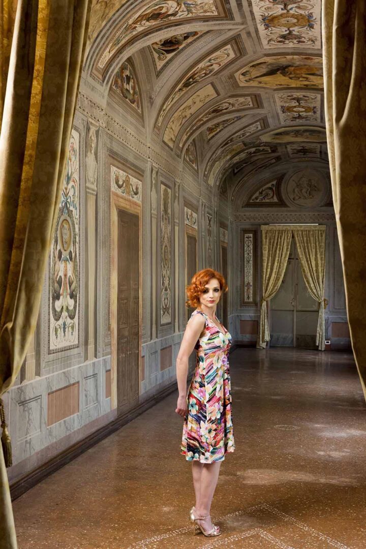 A woman in a floral dress standing in an ornate room.