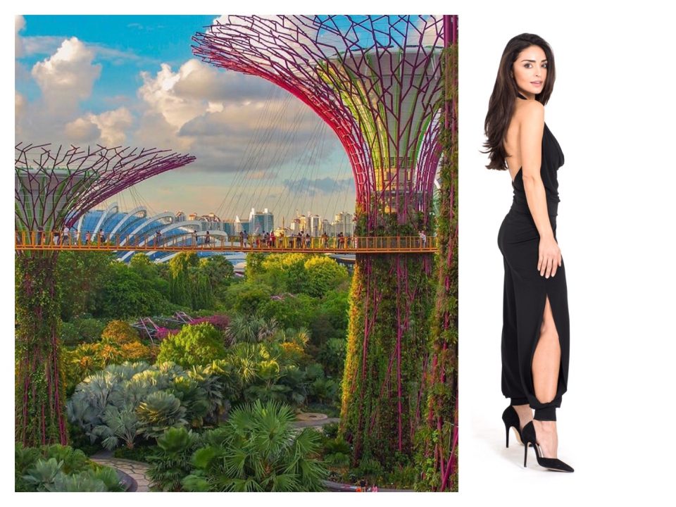 A woman in a black dress standing next to a tree in singapore.