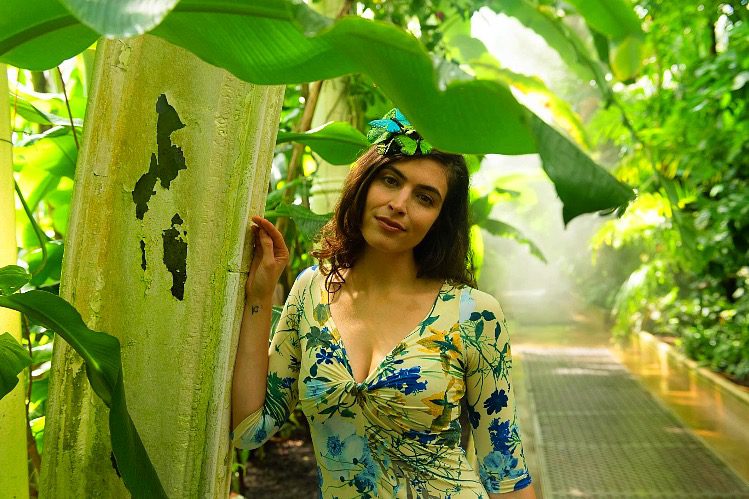 A woman in a floral dress posing in a tropical garden.