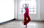 A woman in a beautiful red Tango apparel balancing on one foot
