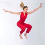 Jumping pose in red tango dance jumpsuit